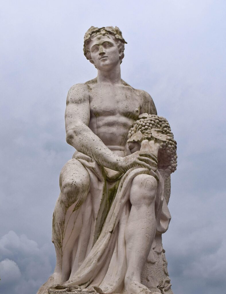 Stone statue of Dionysus, the ancient Greek god of wine, seated outdoors and holding a bunch of grapes, with visible moss and weathering.